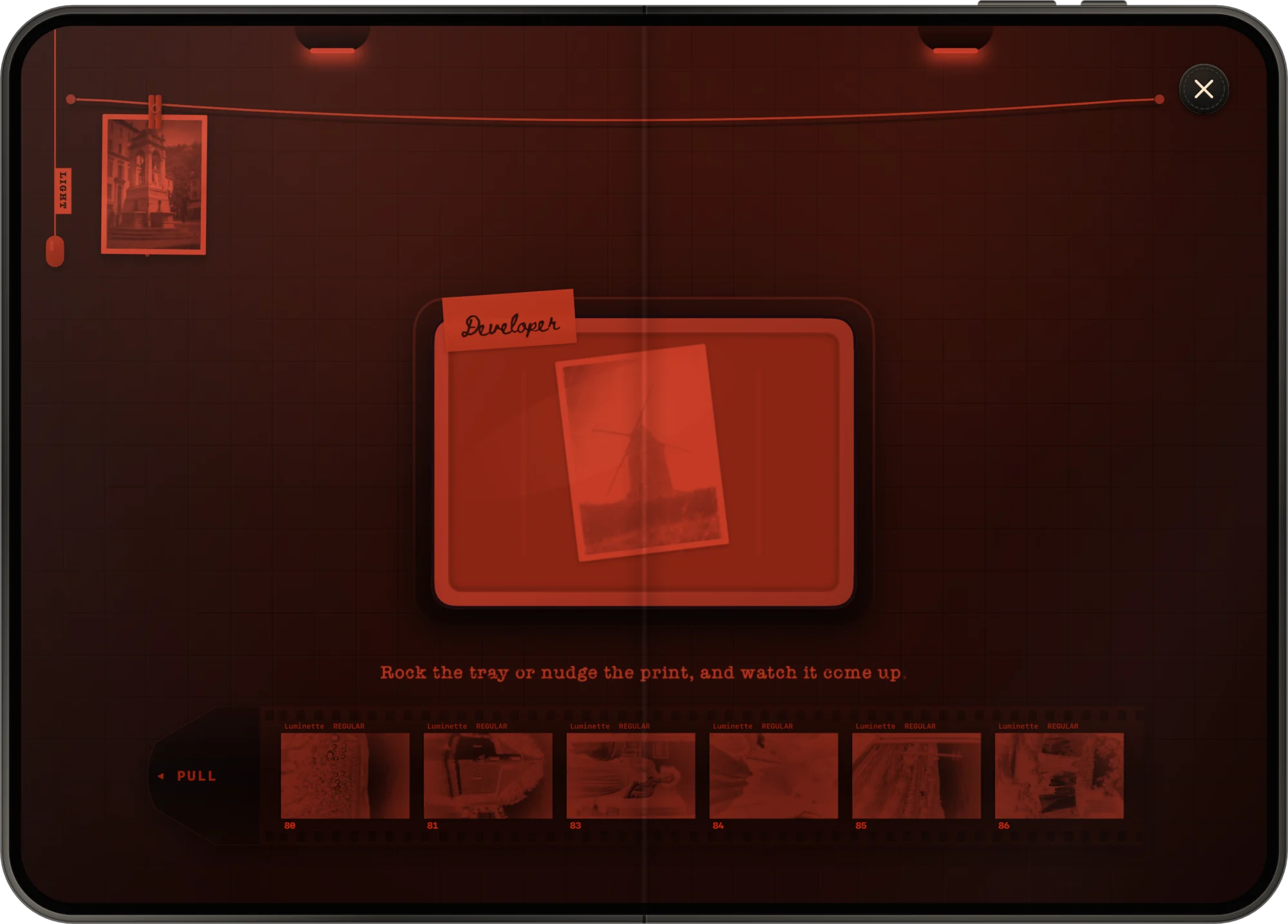 The darkroom across both screens of iPhone Duo, with prints drying on the line.